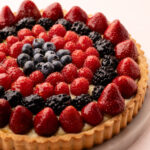 Top view of a freshly baked classic fruit tart with strawberries, raspberries, blackberries, and blueberries.