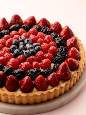 Top view of a freshly baked classic fruit tart with strawberries, raspberries, blackberries, and blueberries.