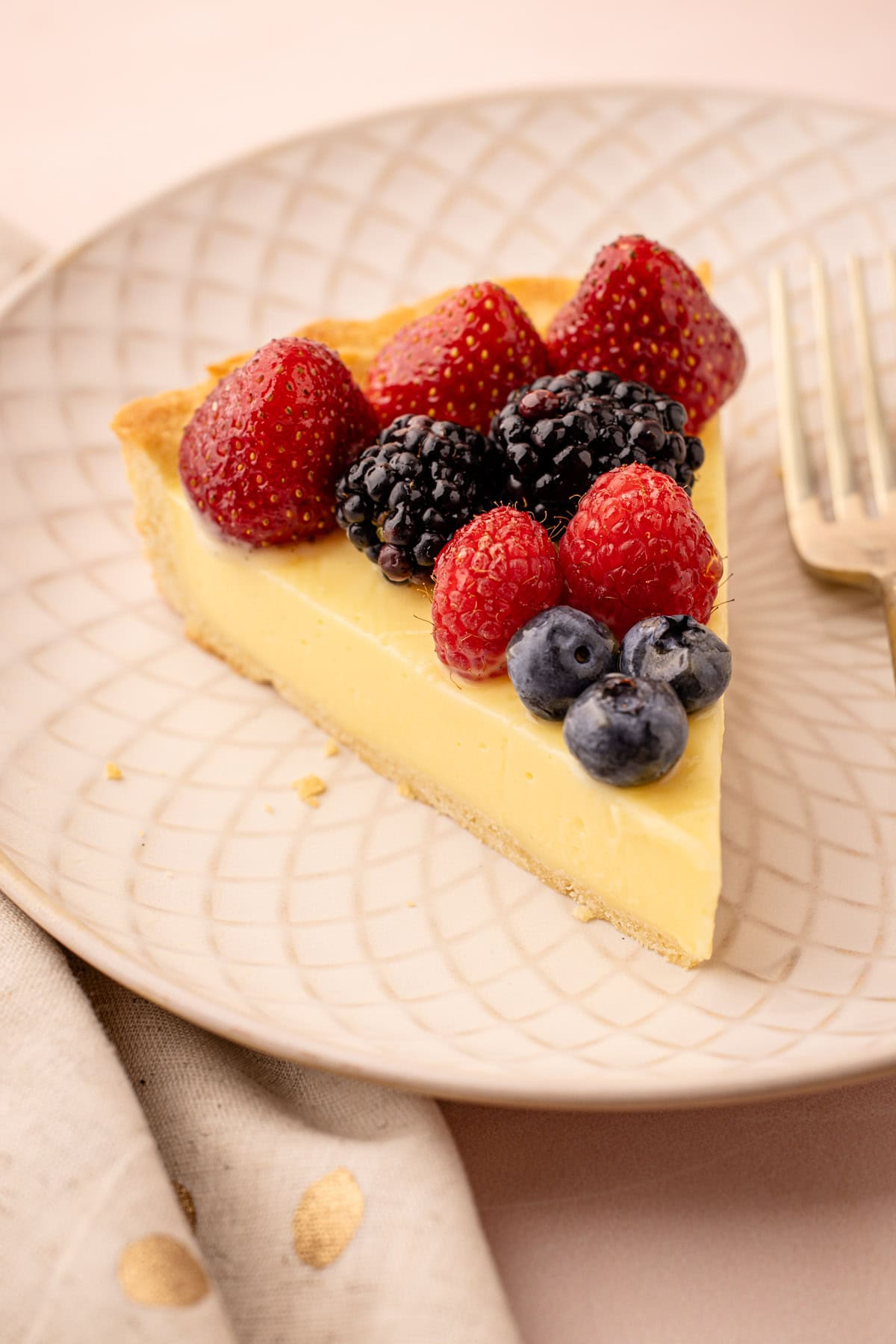 Fresh fruit tart slice with strawberries, blackberries, raspberries, and blueberries.