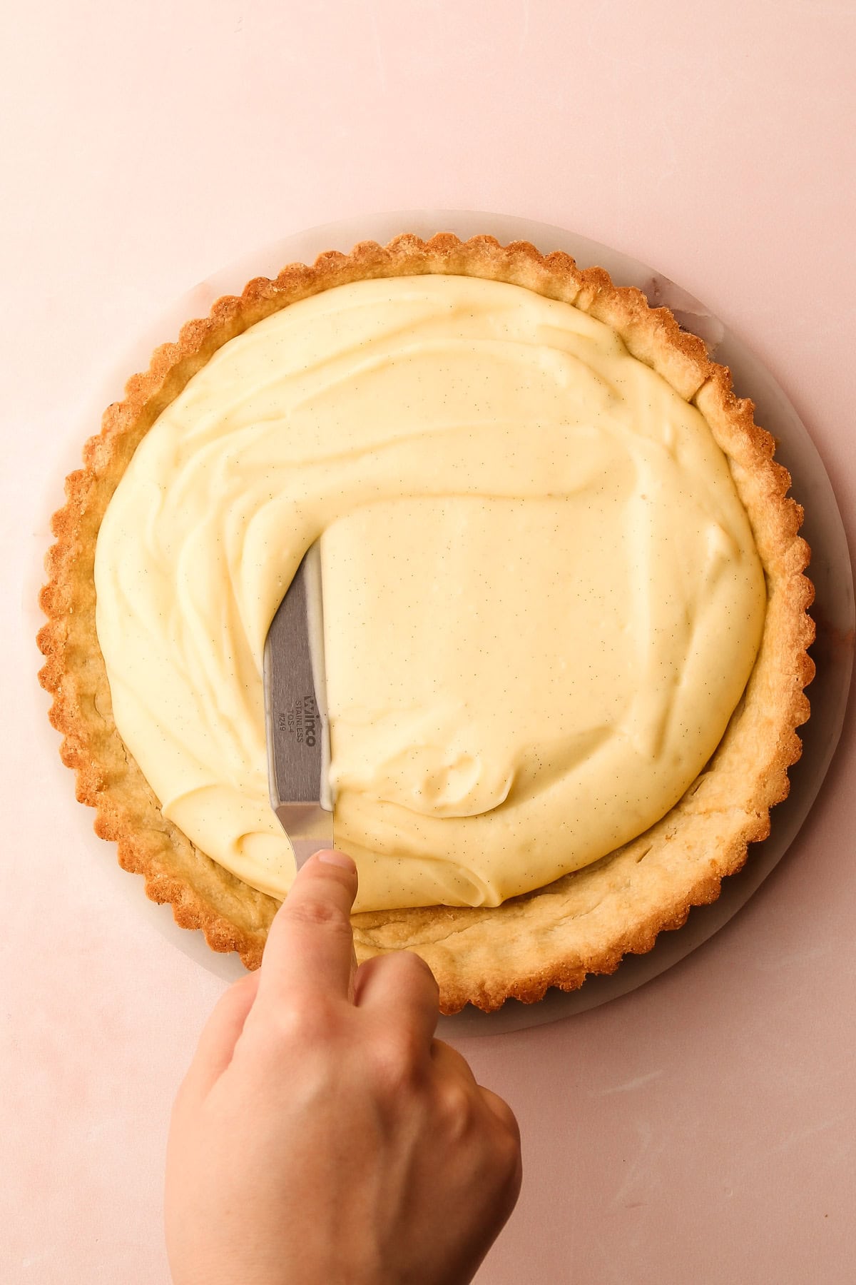 Spreading pastry cream into a tart shell for a fresh fruit tart.