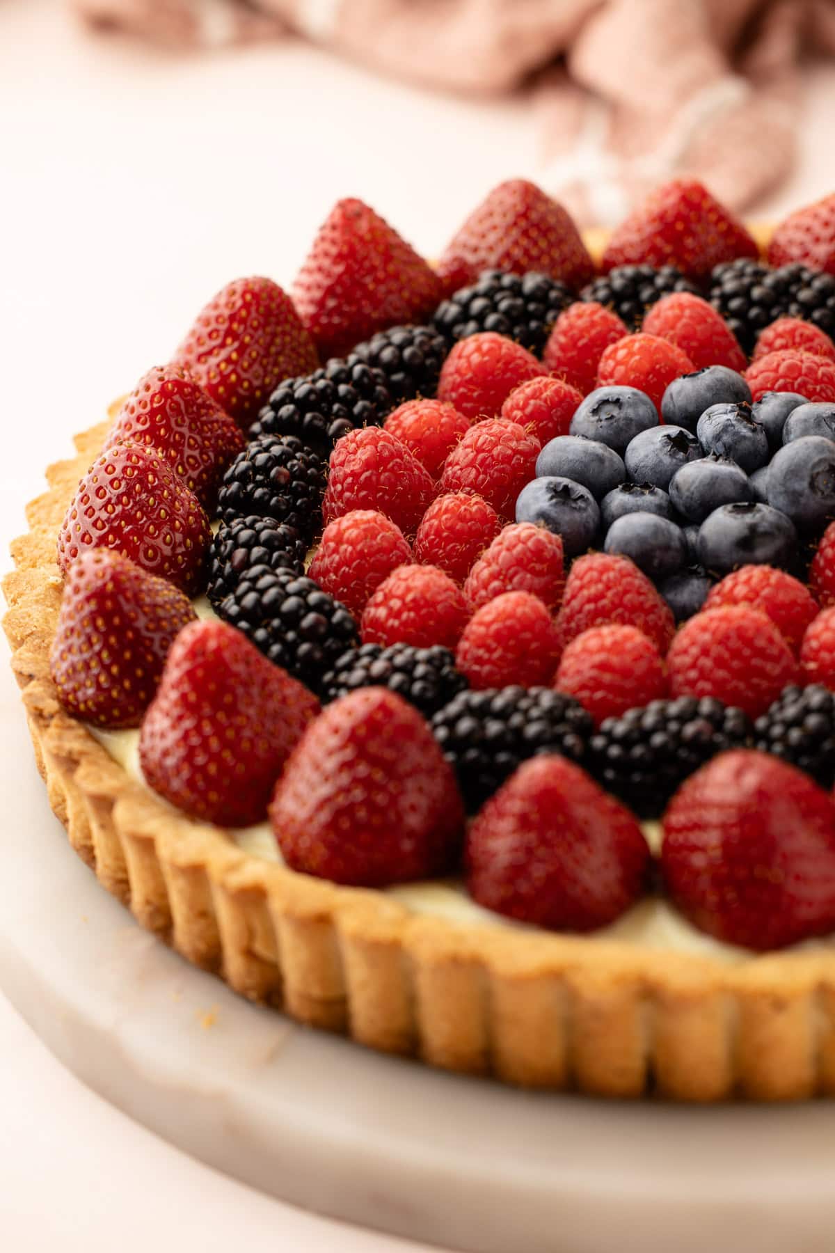 Close-up of a classic fresh fruit tart with strawberries, blackberries, raspberries, and blueberries.