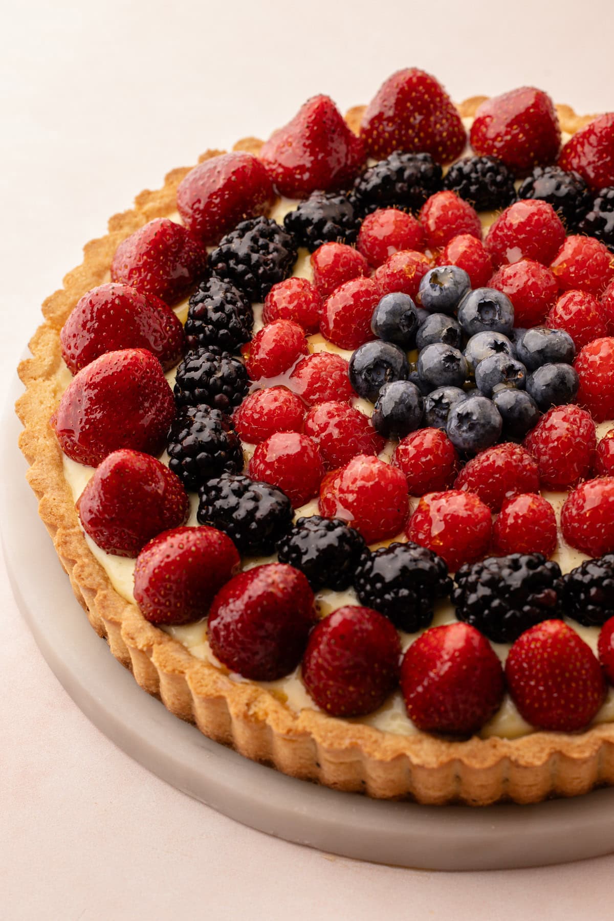 Top view of a freshly baked classic fruit tart with strawberries, raspberries, blackberries, and blueberries.