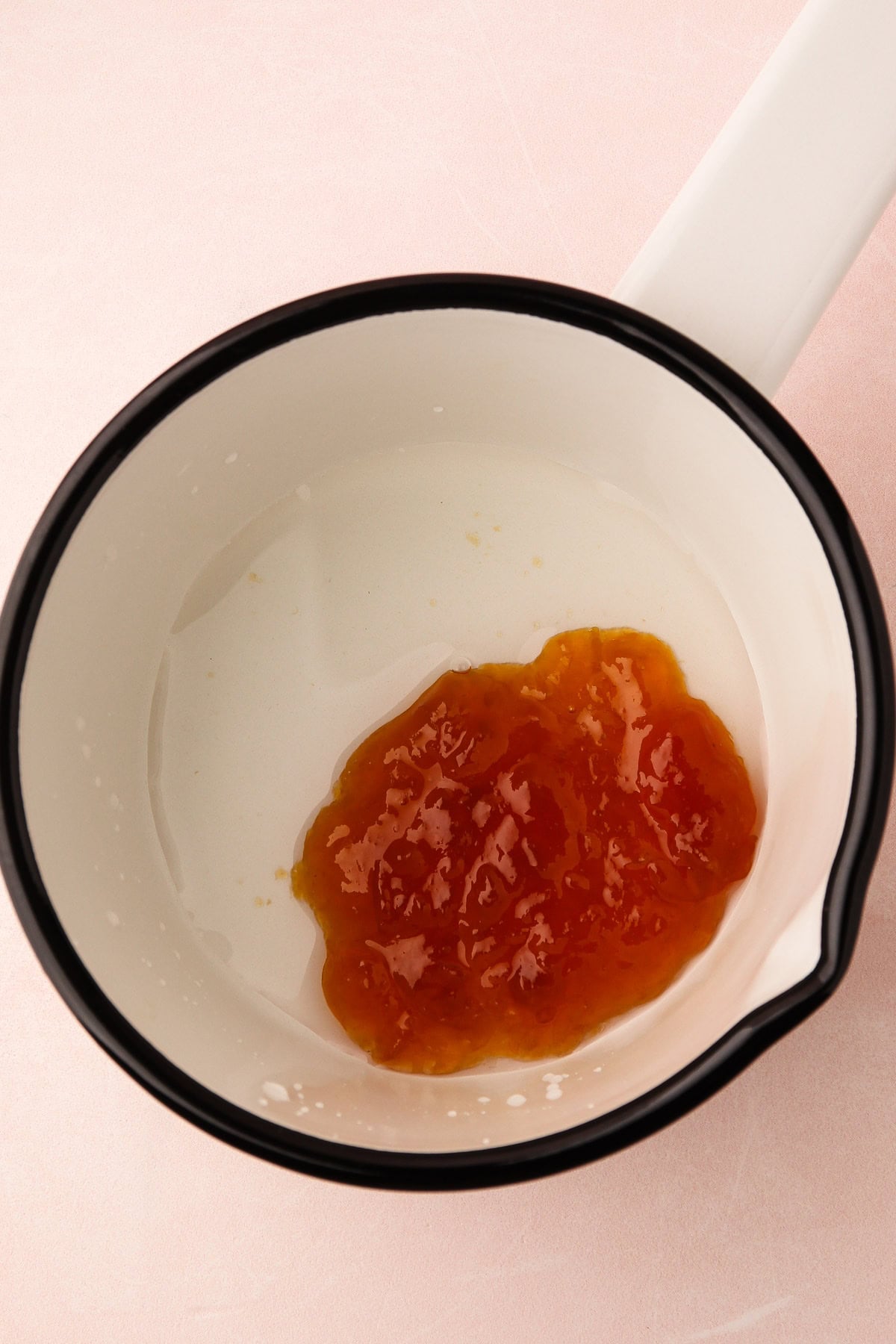 Apricot preserves and water in a saucepan.