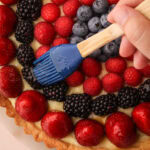 Brushing fruit glaze onto a berry tart for a professional-looking finish.