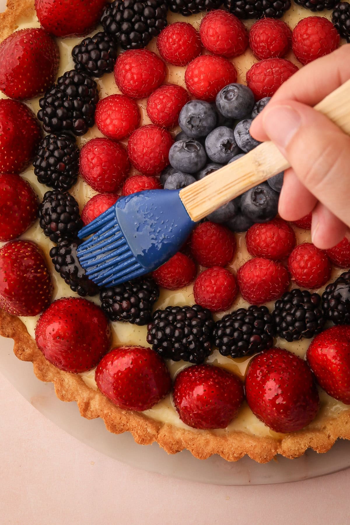 Brushing fruit glaze onto a berry tart for a professional-looking finish.