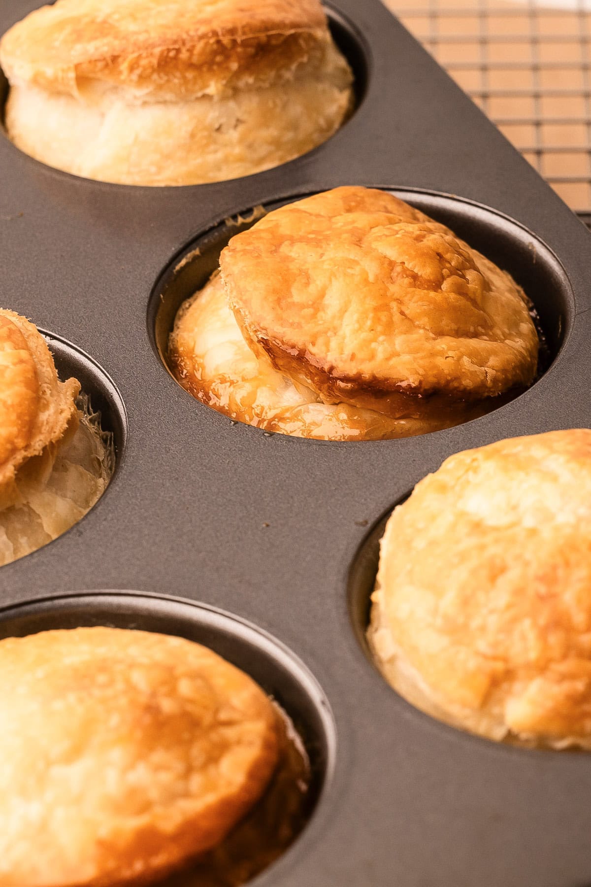 Baked mini peach tarte tatins in a muffin tin, golden and flaky.