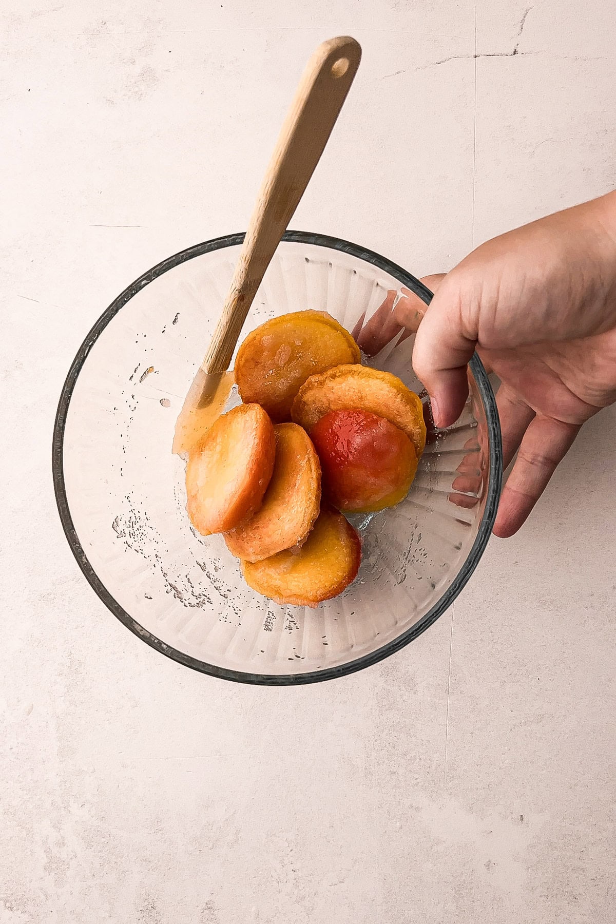 Sliced peaches in a glass bowl, ready for a peach tarte tatin recipe.