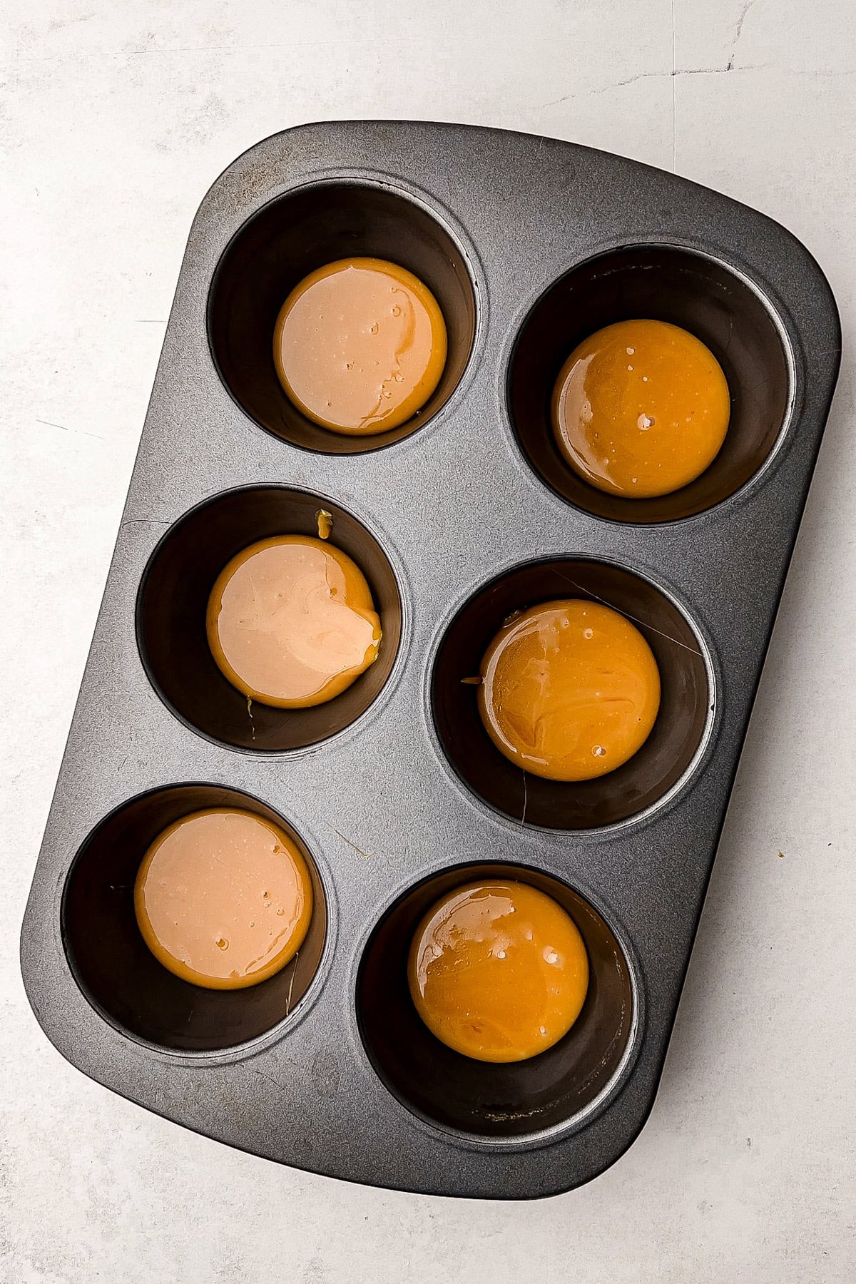 Caramel sauce in a muffin tin.