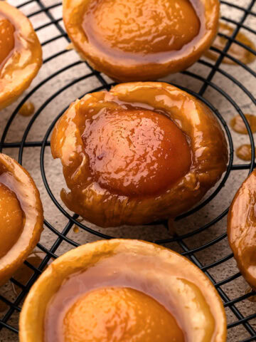 Freshly baked mini peach tarte tatins cooling on a wire rack.