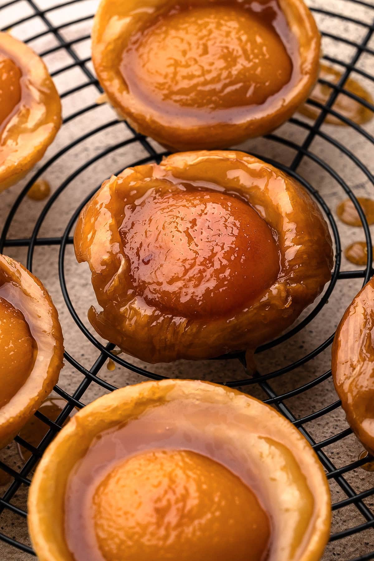 Freshly baked mini peach tarte tatins cooling on a wire rack.