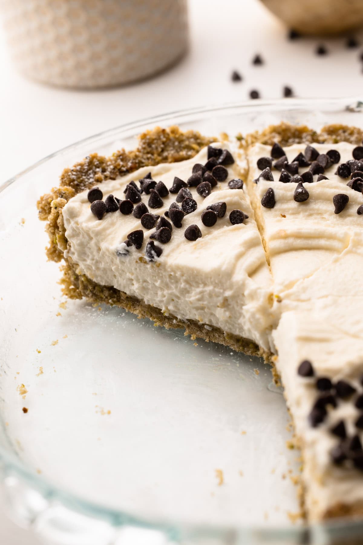 Tarte aux cannoli sans cuit partiellement en tranches dans un plat à tarte en verre.