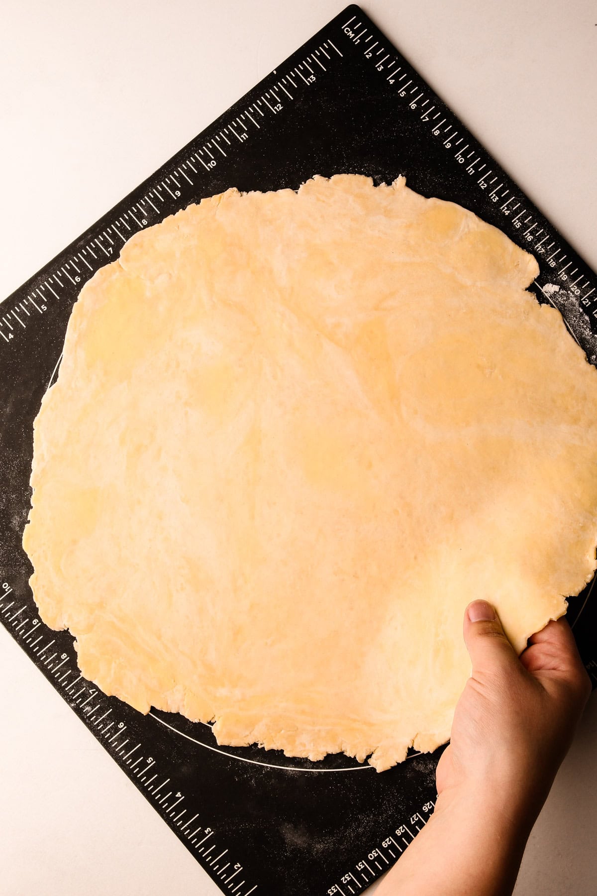 Rolled-out pie dough on a pastry mat.