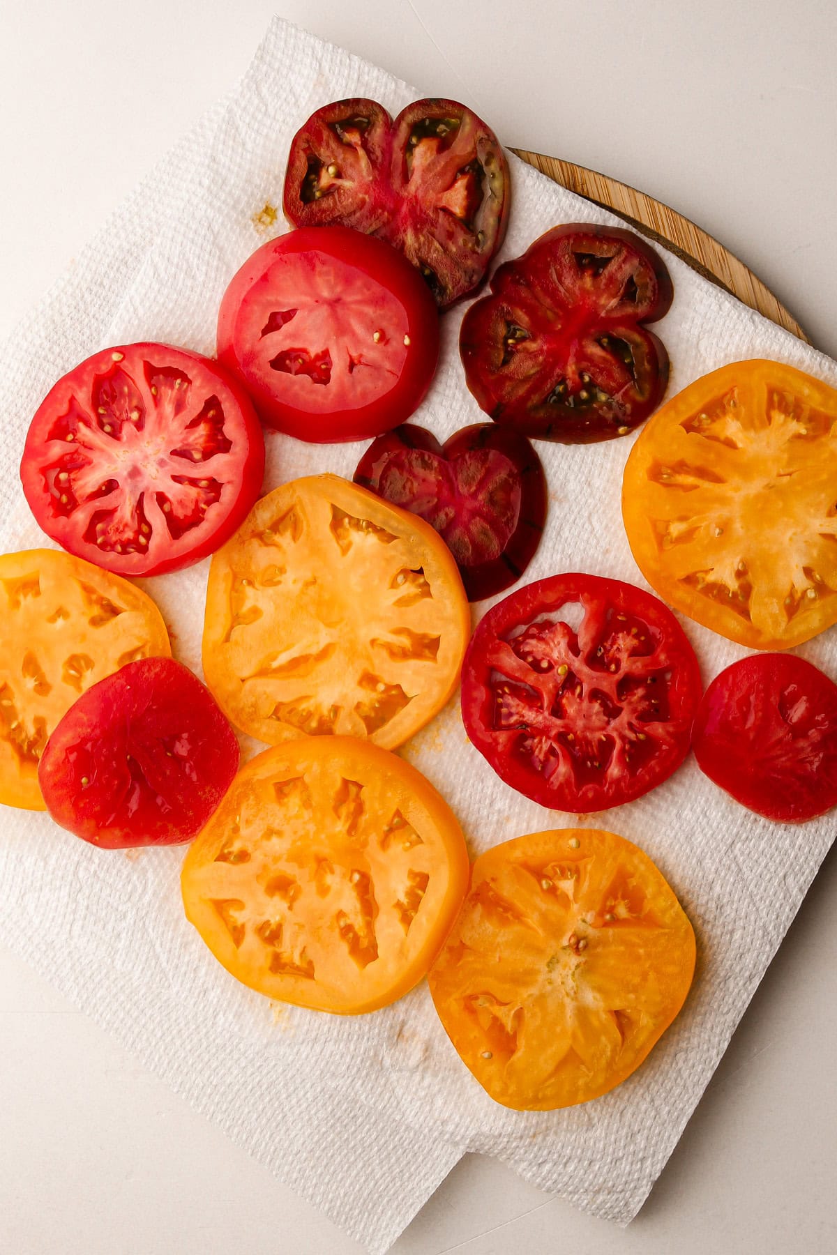 Slices of heirloom tomatoes draining on a paper towel.