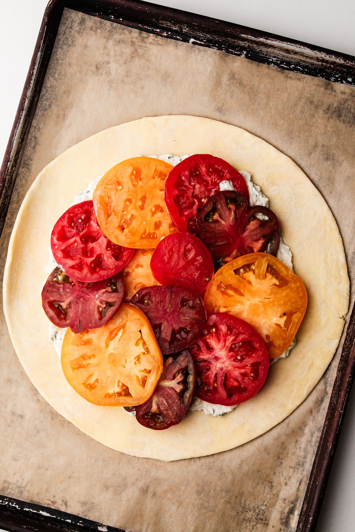 Rolled-out dough topped with a mixture of crème fraîche and heirloom tomato slices.