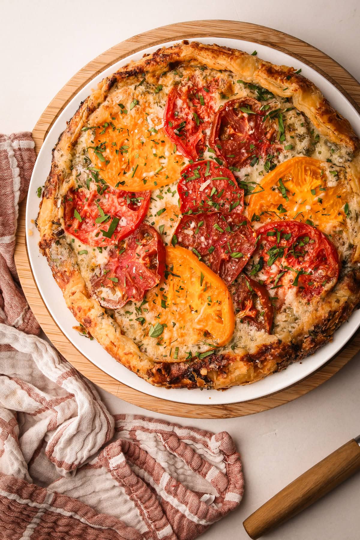 Freshly baked tomato galette with heirloom tomatoes and herbs on a white plate.