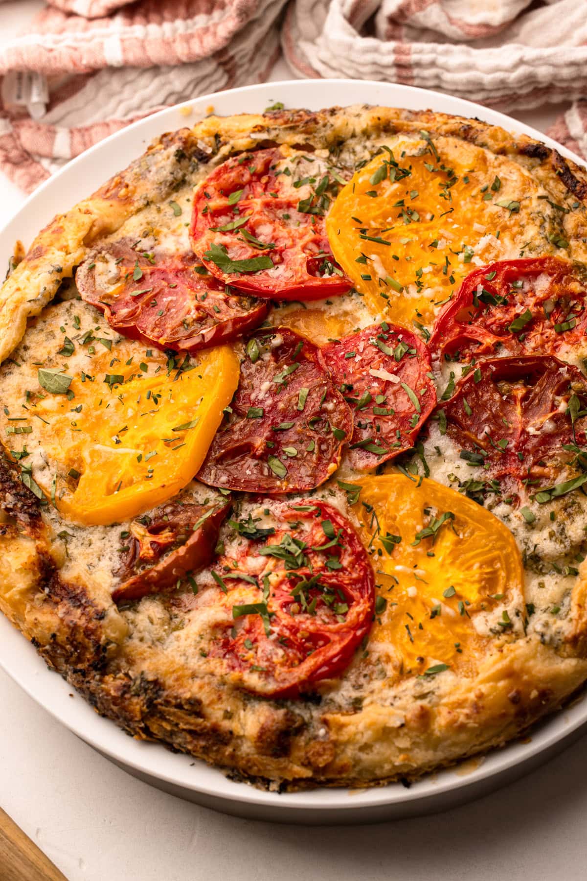 A baked tomato galette topped with heirloom tomatoes and fresh herbs.