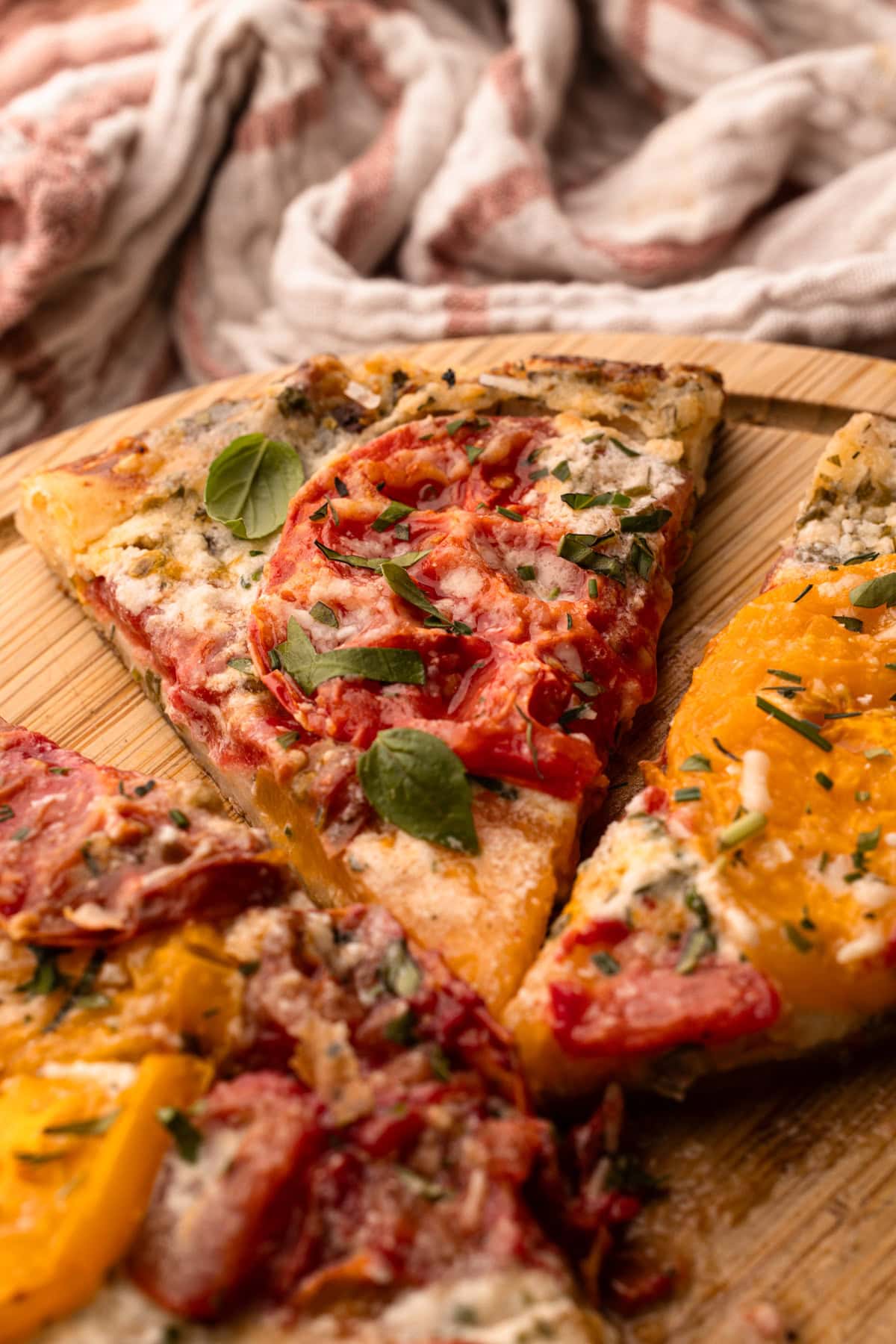 Sliced tomato galette with fresh basil on a wooden board.