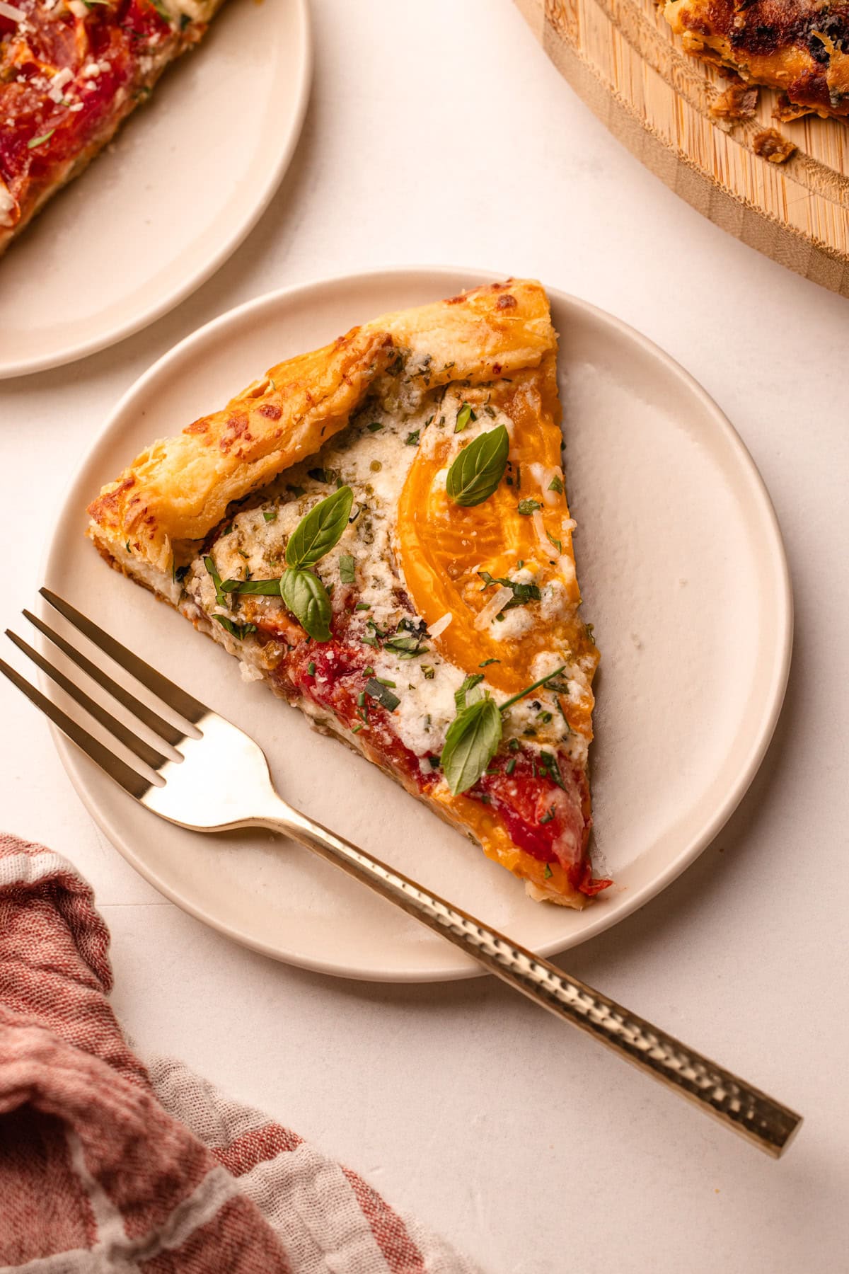 A single slice of tomato galette on a white plate with a fork.