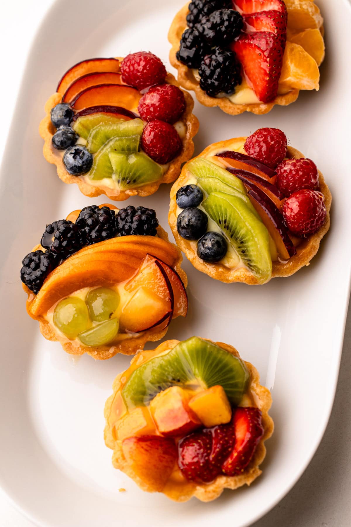 Mini glazed fruit tarts arranged on a tray.