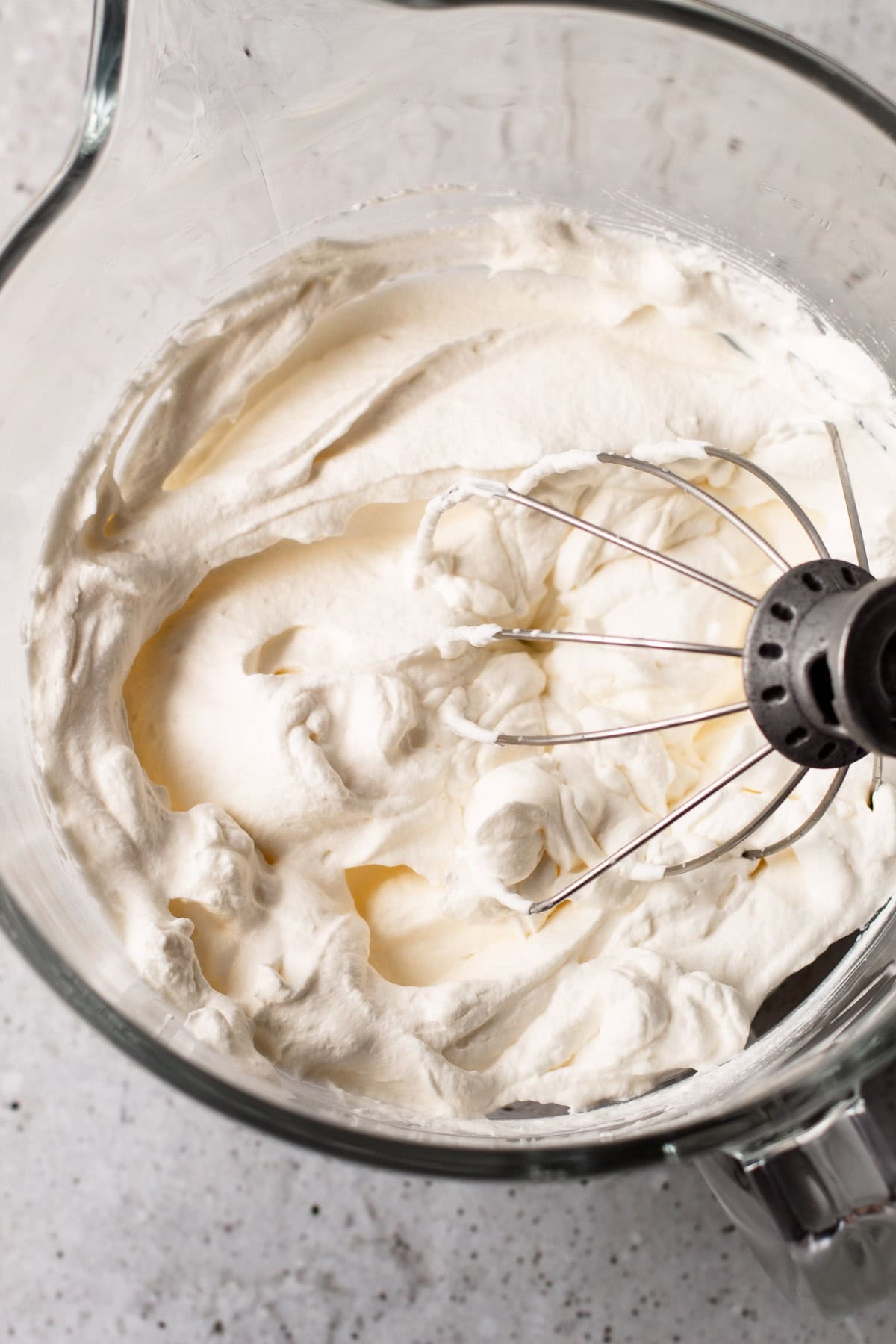 Freshly whipped cream in a glass mixing bowl.