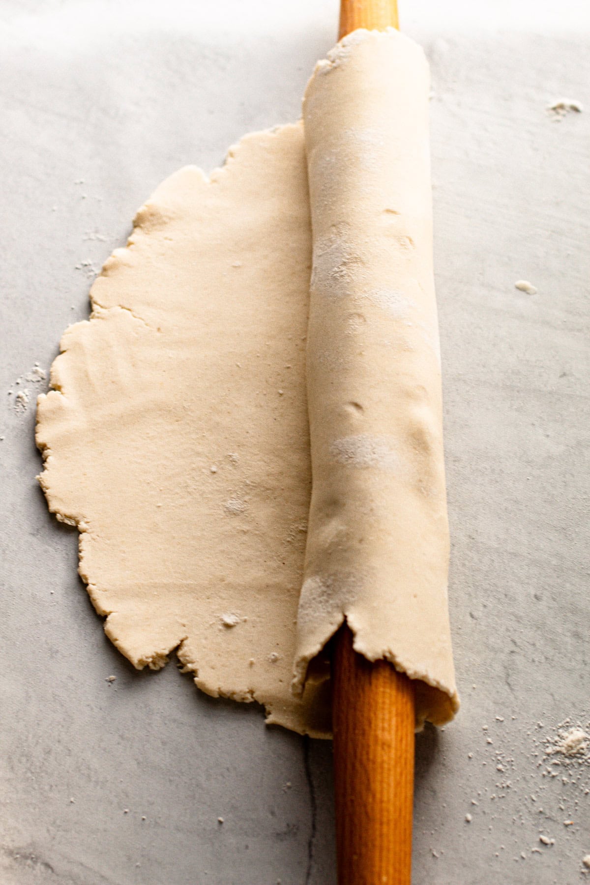 Gluten free pie dough rolled out and around a rolling pin to show how easy it is to work with.