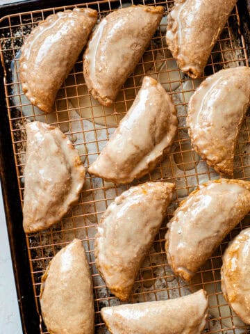 Baked and glazed pumpkin pasties on a cooling rack.