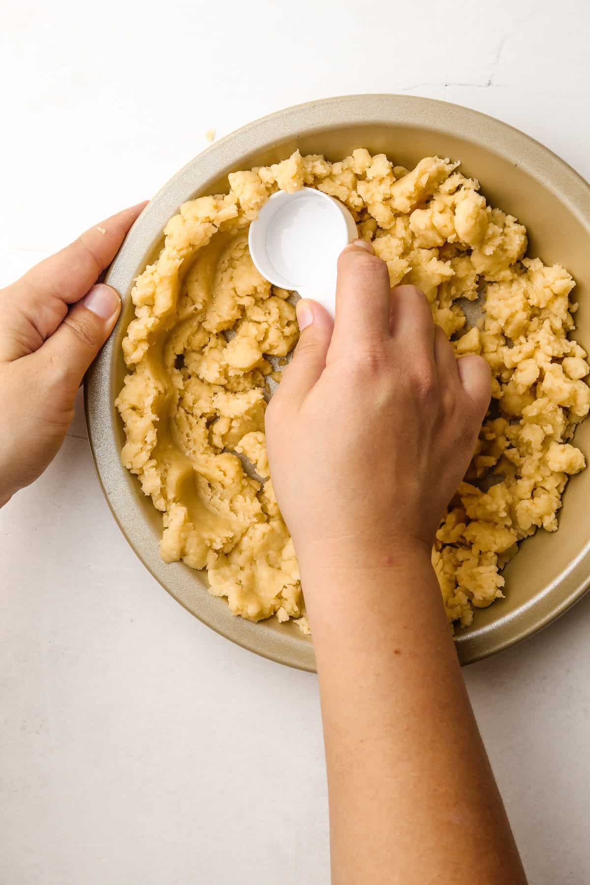 Pressing in the melted butter pie crust with a measuring cup.