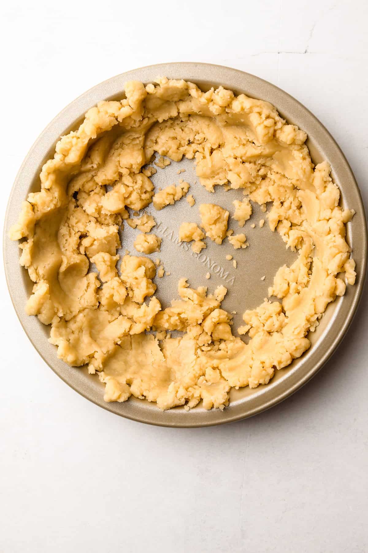 Pressing in the melted butter pie crust with a measuring cup.