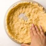 Hands pressing in the pie crust to a baking tin.