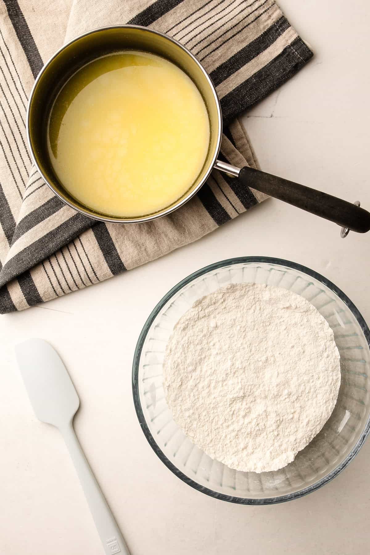 A bowl of flour and a pot of milk and cream ready to prepare an easy melted butter pie crust.