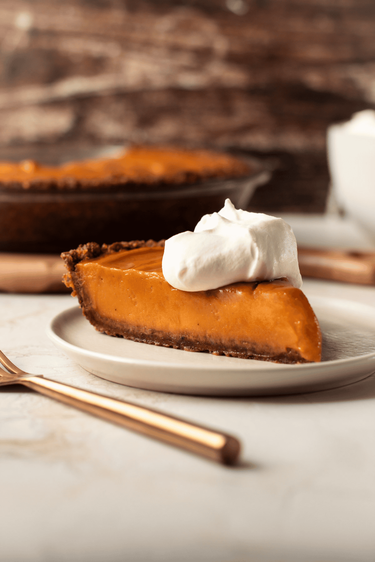 A slice of sweet potato pie on a plate with a dollop of whipped cream.