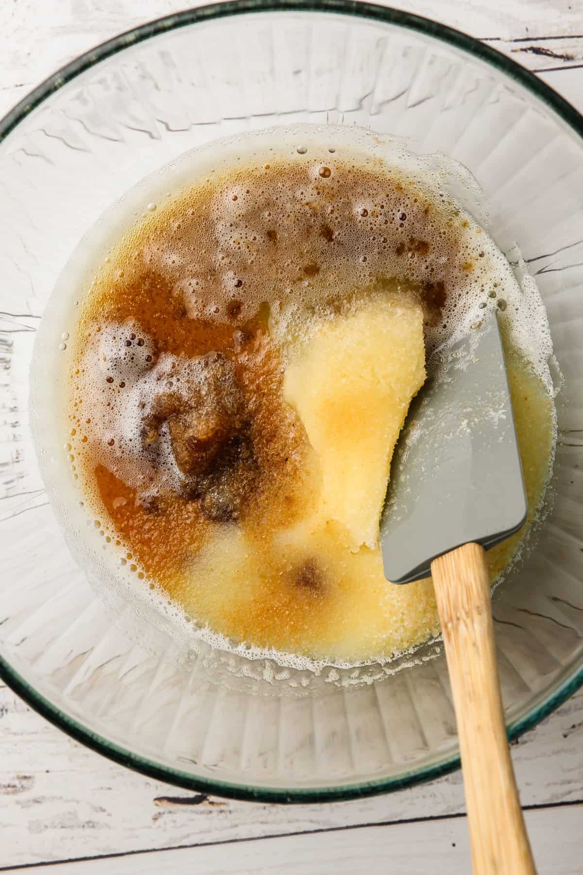 Browned butter and sugar being mixed in a glass bowl for buckwheat chocolate chip cookies.