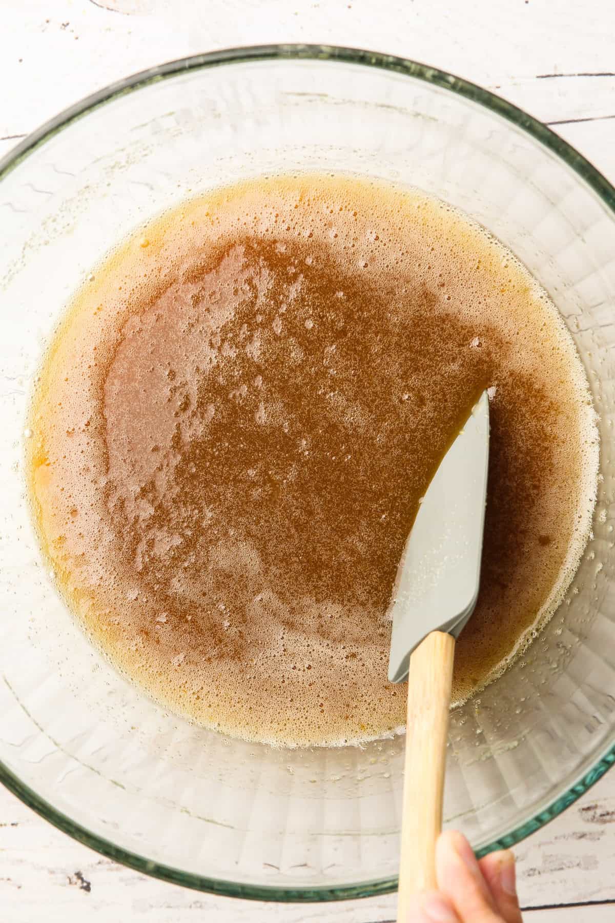 A smooth mixture of melted butter and sugar in preparation for oat buckwheat chocolate chip cookies.