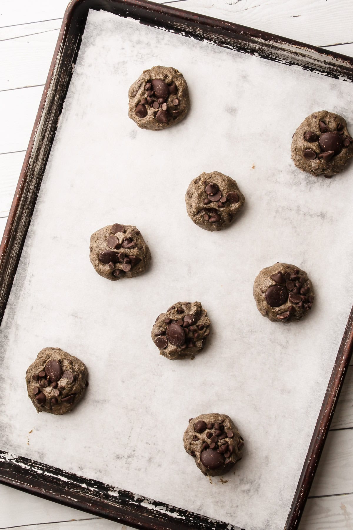 Cookie dough balls arranged on a parchment-lined baking sheet ready to bake.