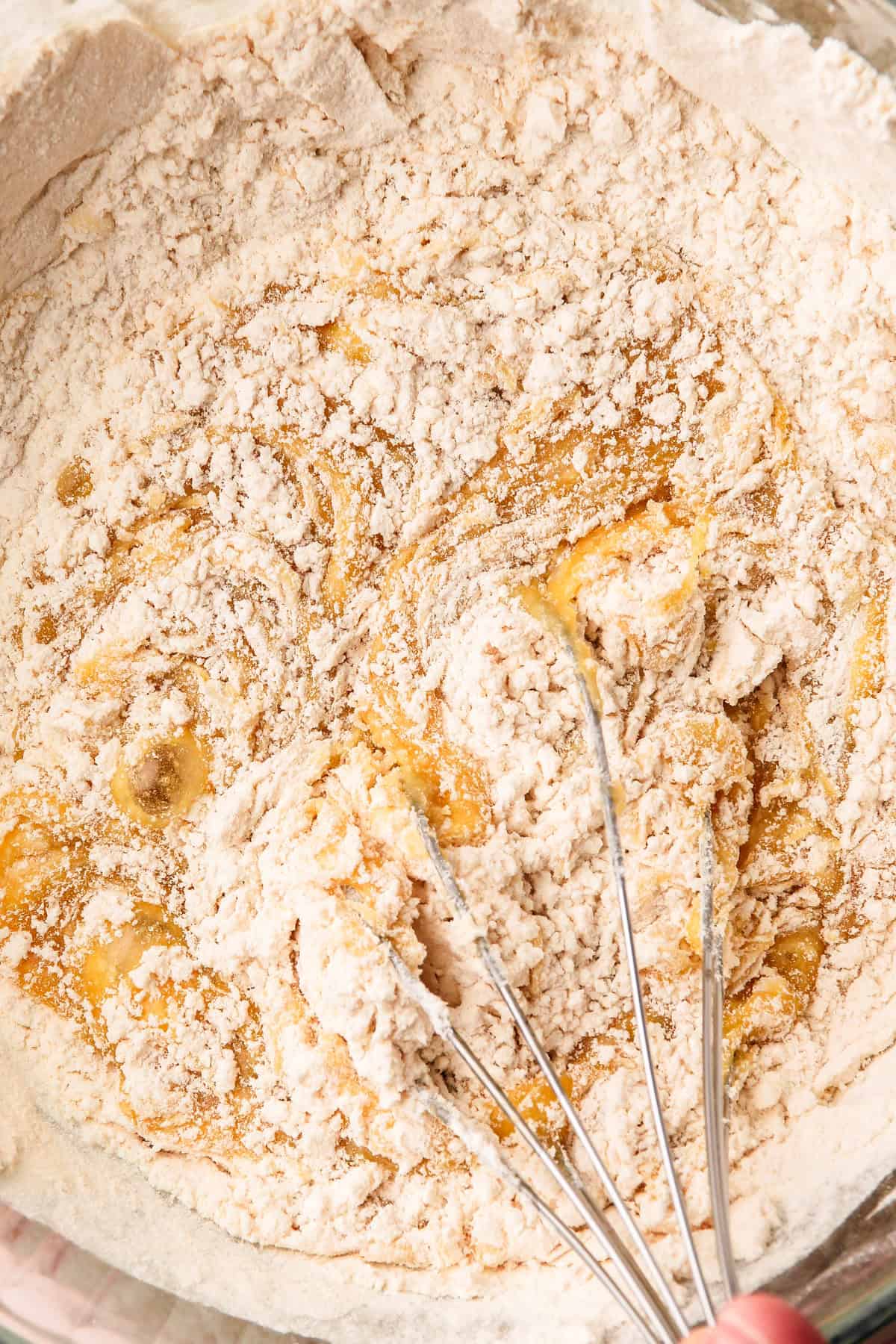 A whisk stirring together the dry and wet ingredients to form the pizzelle batter.