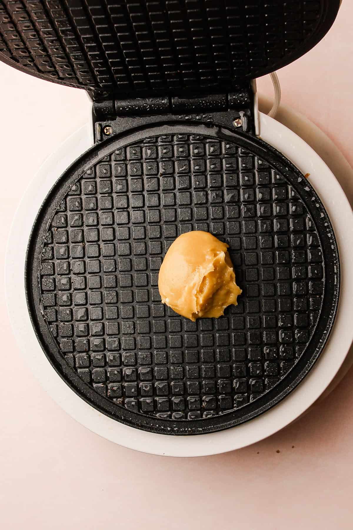 A scoop of pizzelle batter placed on the iron, ready to be pressed and baked.