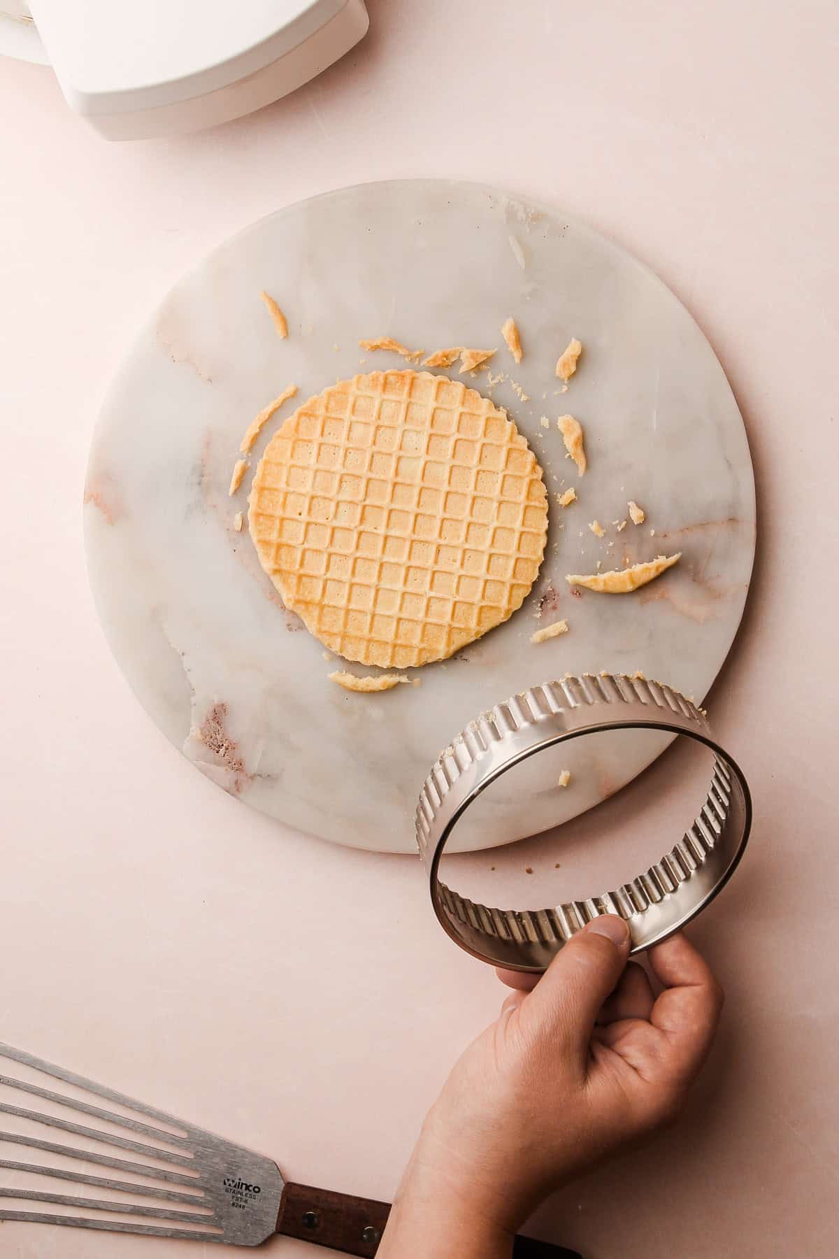 A trimmed pizzelle with crisp edges, surrounded by small scraps.