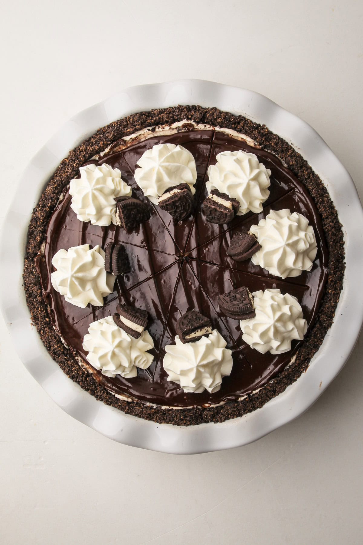 A no-bake oreo pie decorated with ganache, oreos and whipped cream.