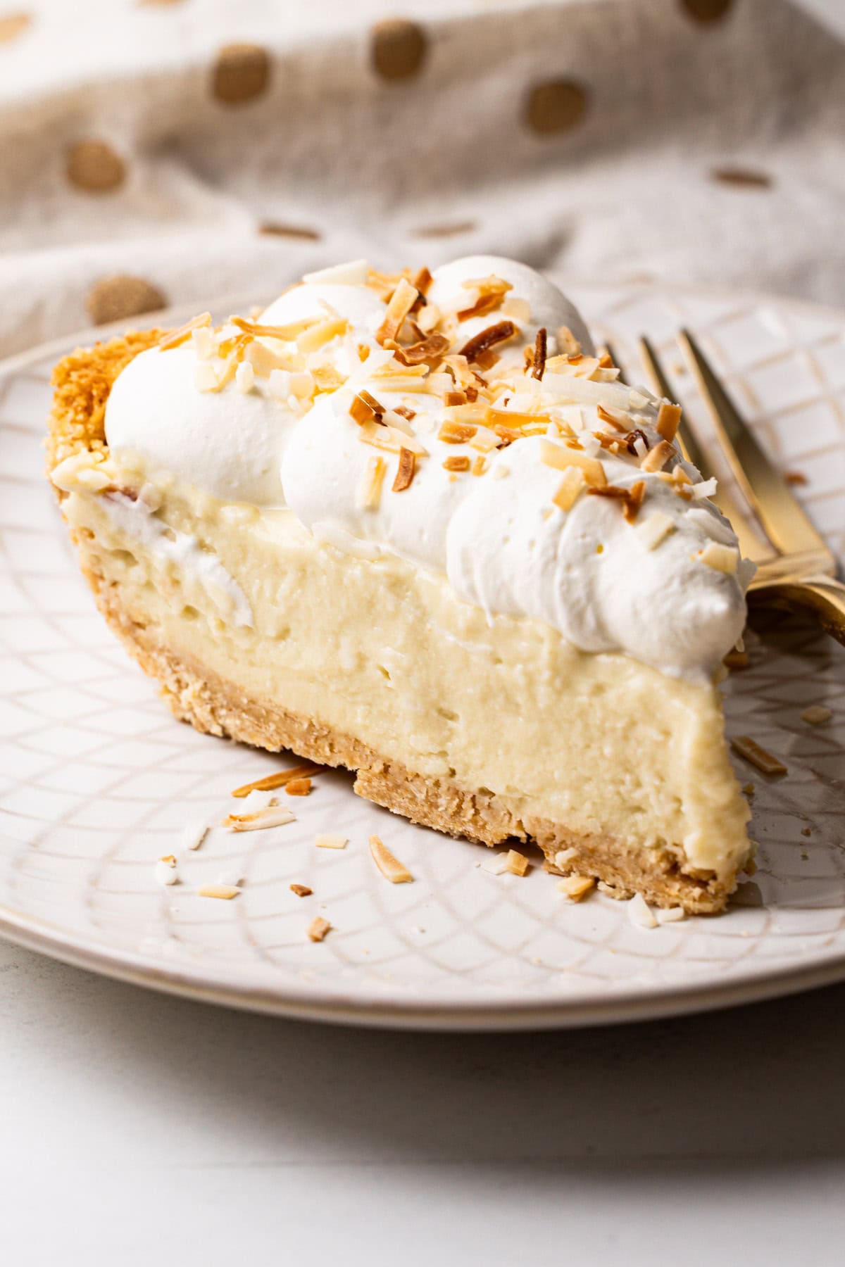 A slice of no-bake coconut cream pie on a plate, showing the creamy layers and cookie crust.