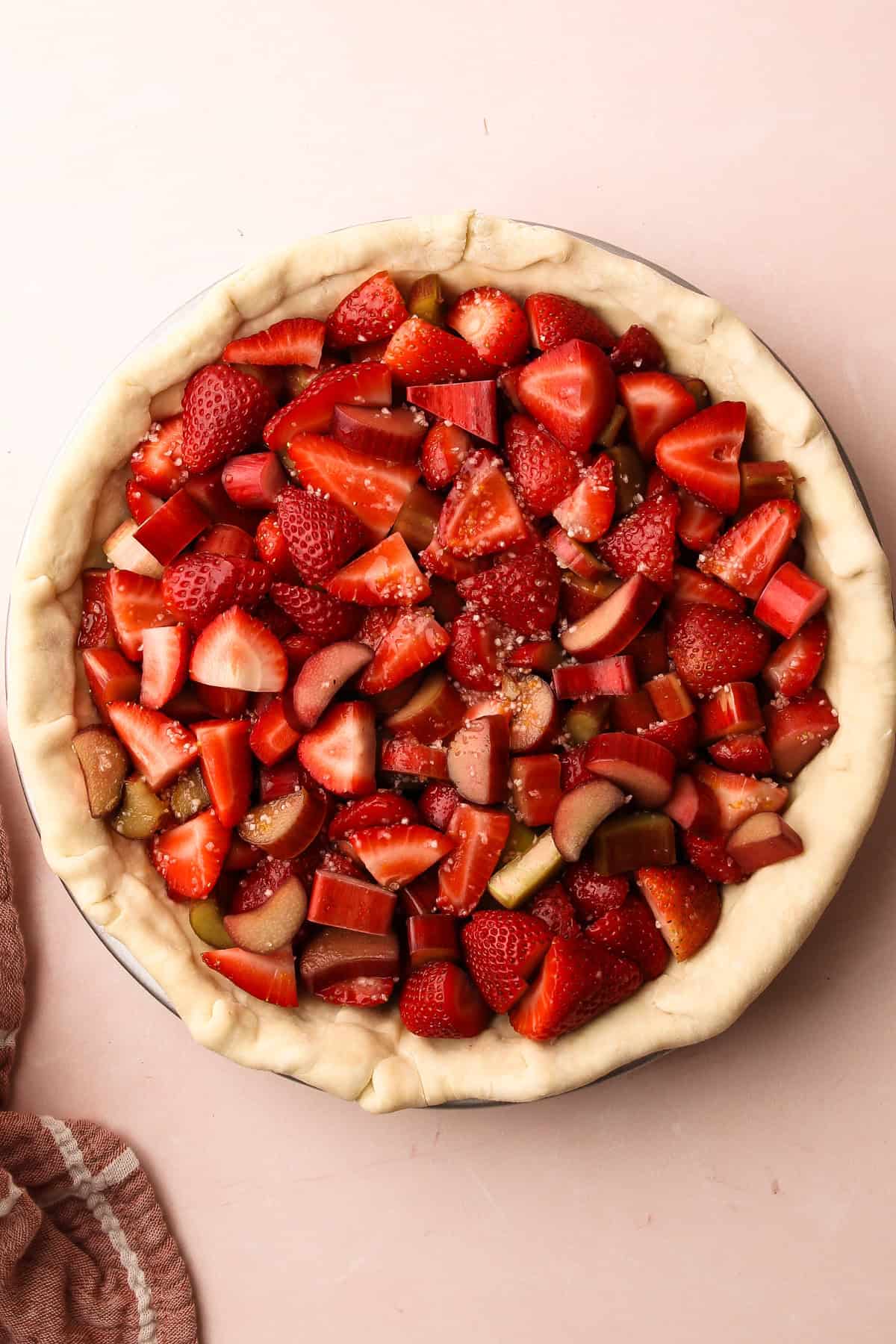 Strawberry rhubarb pie filling inside a pastry lined pie tin waiting for the top pastry.