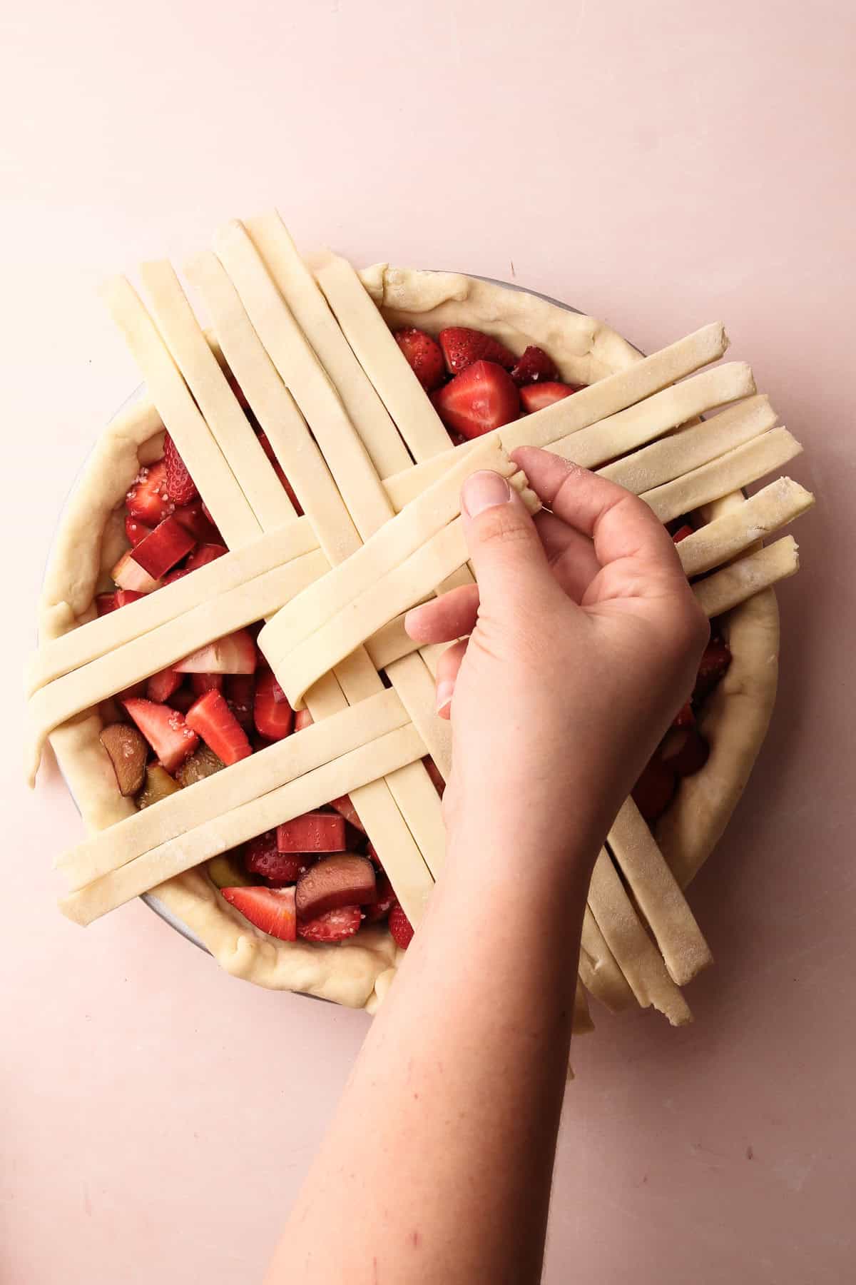 Weaving a lattice on a strawberry rhubarb pie.
