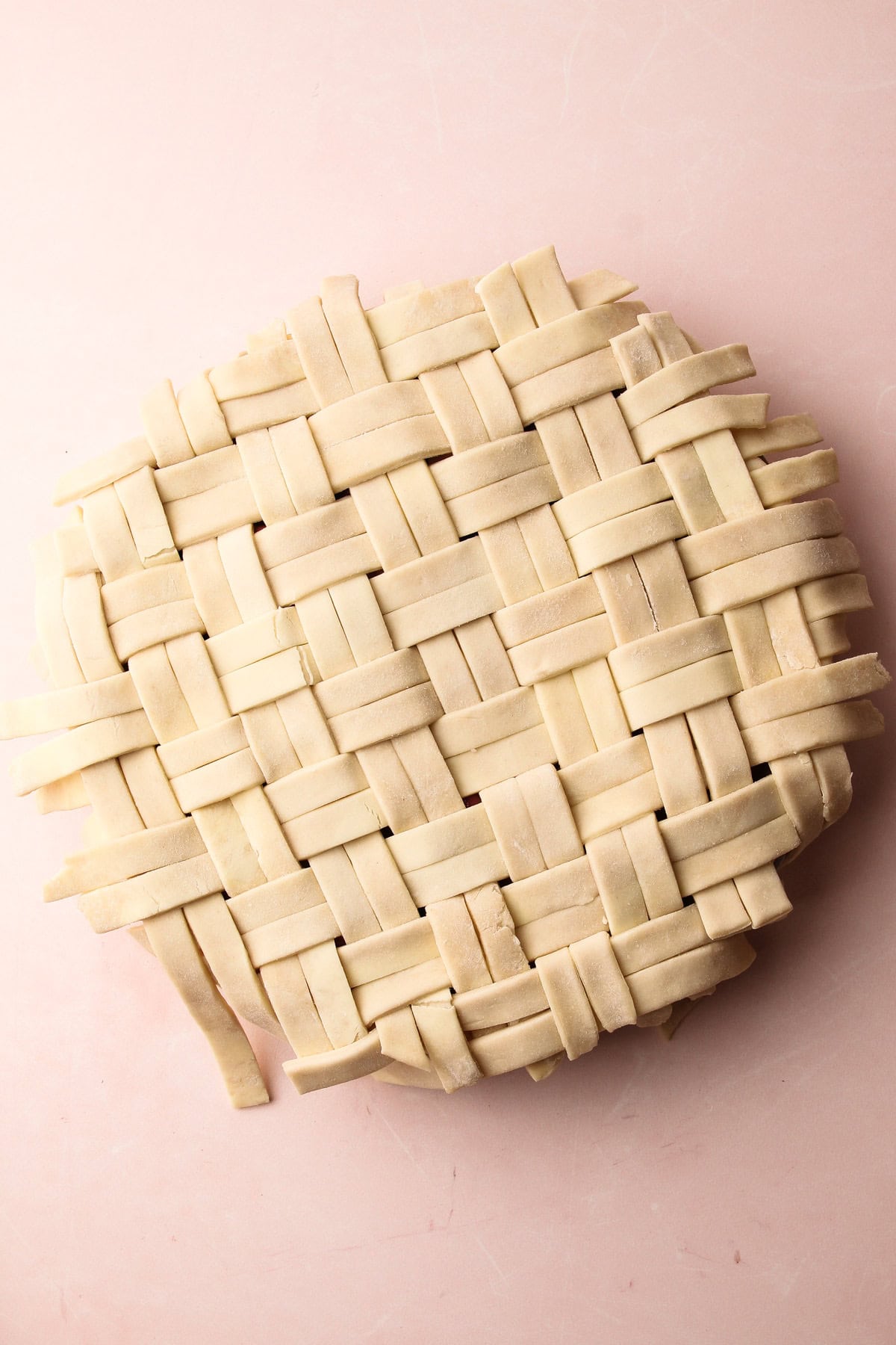 A lattice on top of an unbaked strawberry rhubarb pie.