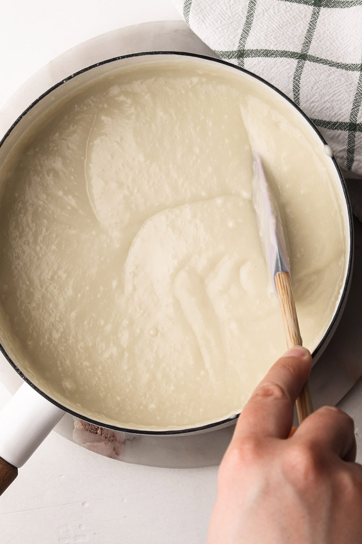 Stirring together thickened coconut pudding in a pot.
