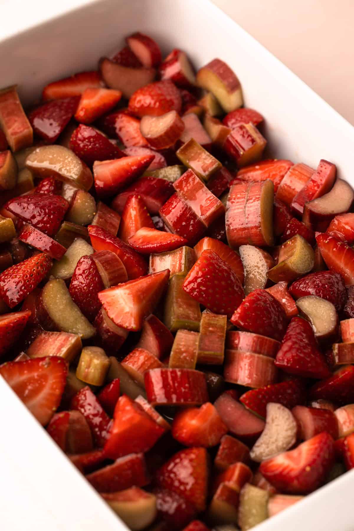 Macerating strawberries and rhubarb in a baking dish.