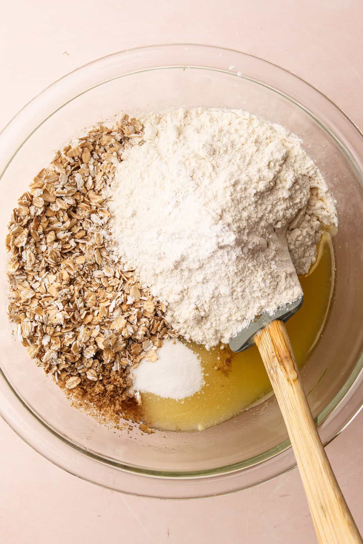 Oats, flour and sugar in a bowl with other ingredients to make a crumble topping.