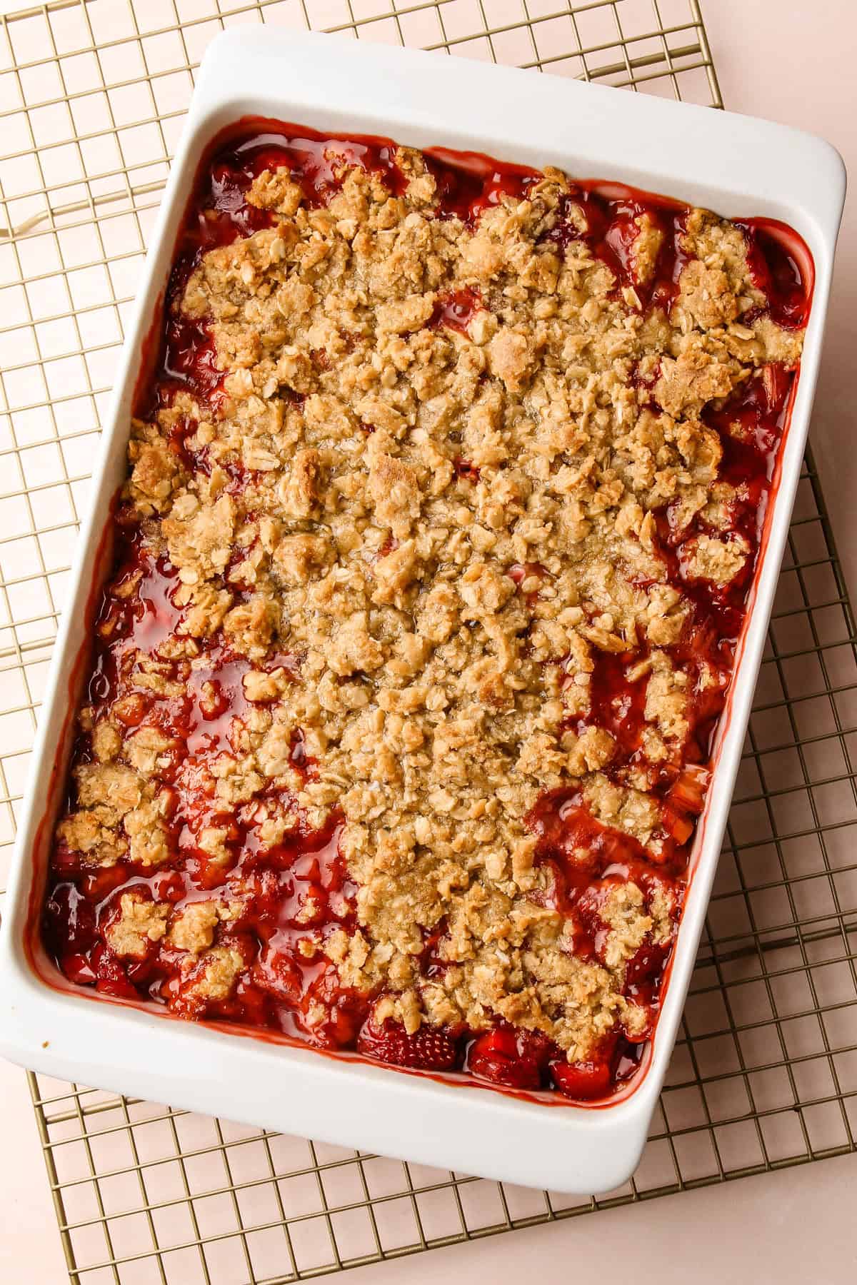 A baked strawberry rhubarb crisp cooling on a rack.