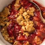A bowl of baked strawberry rhubarb crisp.