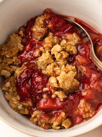 A bowl of baked strawberry rhubarb crisp.