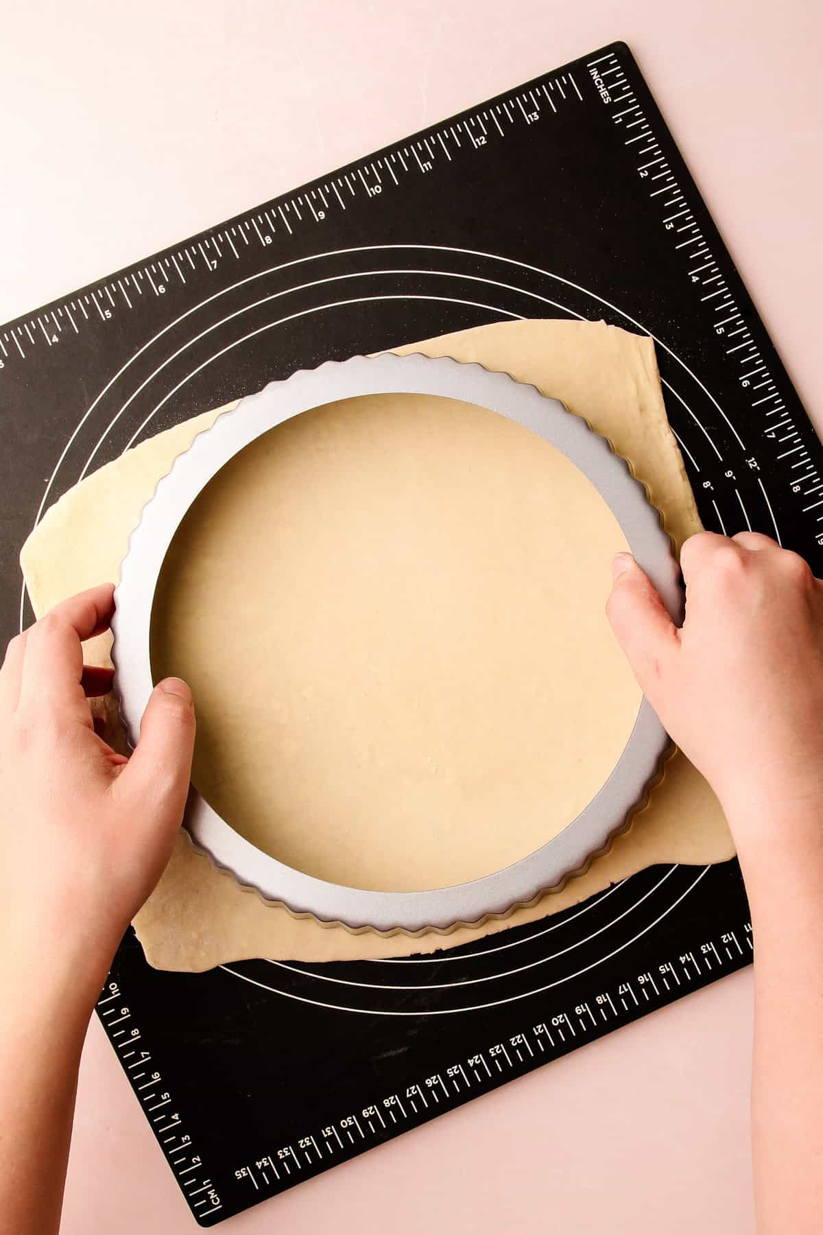 Puff pastry being trimmed with a tart pan for a puff pastry asparagus tart.