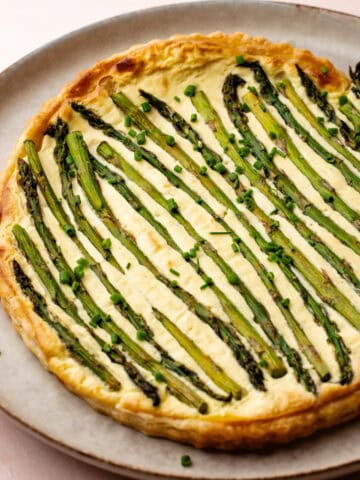 A baked lemon asparagus tart topped with roasted asparagus and chopped chives.